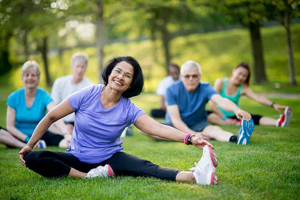 Group of adults stretching on grass at a public park
